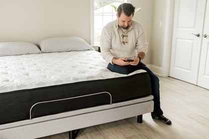 Man sitting on end of RV Mattress looking at his phone